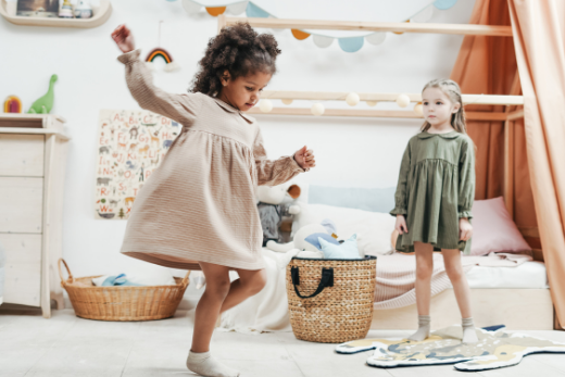 two young girls in a bedroom playing and dancing