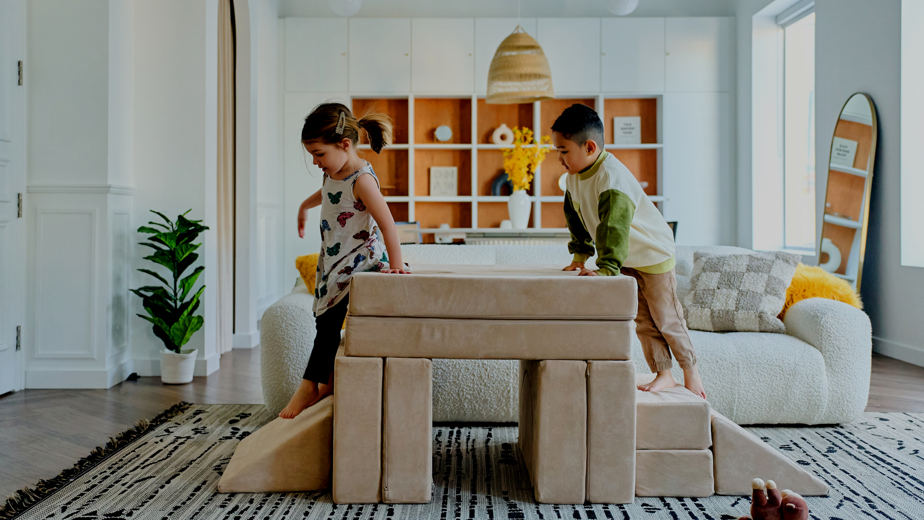 kids play couch in sand with two children climbing over a build in a living room